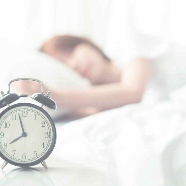 picture of a woman sleeping in and an alarm clock